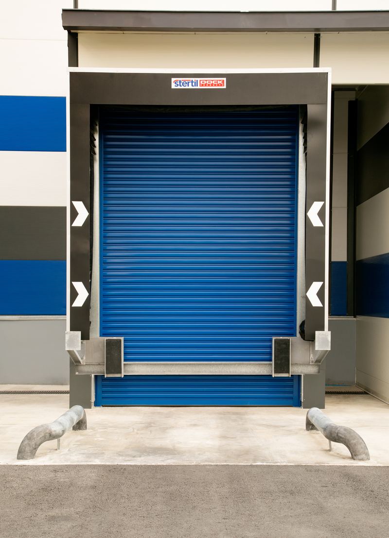 Stertil Dock Products blue rolling shutter door on a warehouse loading dock with white and blue exterior.