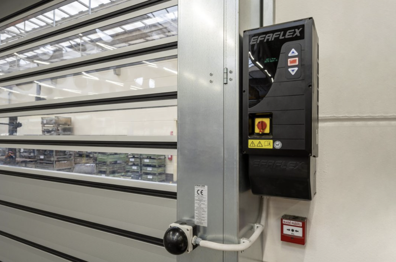 EFAFLEX high-speed industrial door with transparent panels and control unit in a warehouse setting.